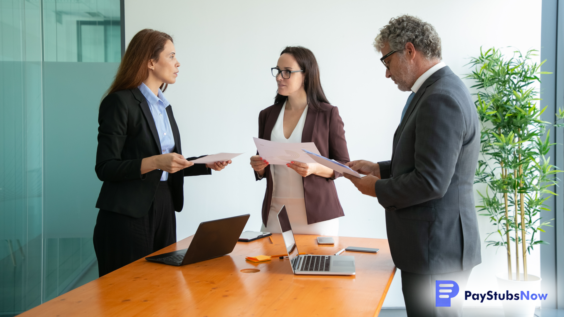 Three professionals stand around a conference table in an office